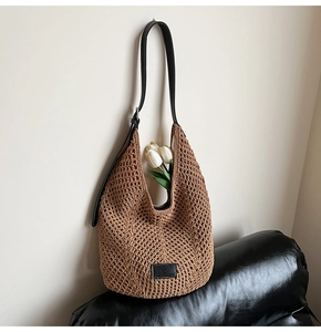 Close-up of brown honeycomb crochet hobo bag with black leather strap and floral detail