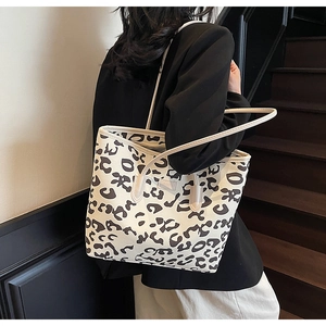 Detail of large leopard print tote bag with cream straps and embossed logo tag