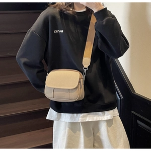 Detailweergave van kaki canvas crossbodytas met brede schouderriem op model