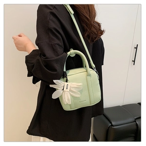Detail showing light green pebble leather handbag with floral charm and adjustable strap