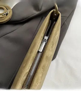 Detail of smooth metal zipper on khaki faux leather shoulder bag with lychee texture