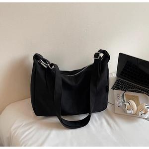 Detail of adjustable strap with silver metal buckle on black canvas dumpling tote bag
