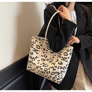 Detailed close-up of a large leopard print canvas tote bag styled with a professional blazer