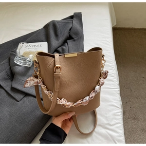 Detail of brown lychee grain bucket bag with floral silk scarf and gold metal chain strap