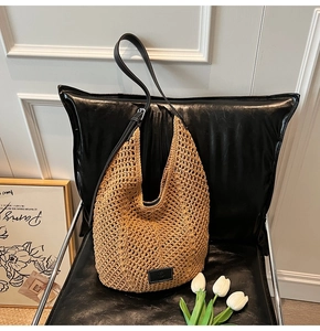 Detail view of brown woven hobo bag with black leather strap and silver buckle on a chair