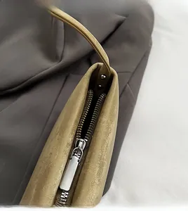 Close-up of premium silver metal zipper and textured leather on a taupe handbag