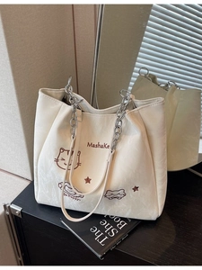 Sac fourre-tout crème à texture plissée avec broderie de chat sur une table noire