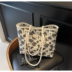 Detail of canvas tote bag showing cow pattern texture and brand leather label