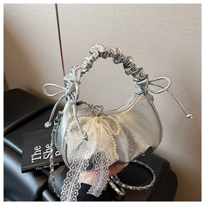 Détail d'un sac demi-lune argenté avec poignée plissée, dentelle et nœud en perles