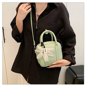 Detail of light green mini crossbody bag with lychee texture and floral pendant charm