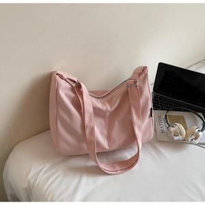 Pink canvas hobo bag with wide strap and silver zipper shown in a cozy lifestyle setting