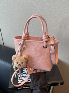 Pink pleated leather bucket bag with teddy bear charm shown from a 45-degree angle