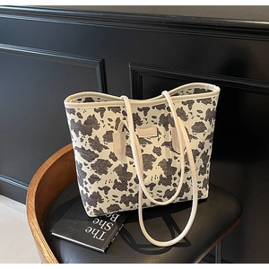 Detail shot of the cow print tote bag with leather logo tag and sturdy double shoulder straps