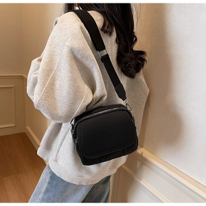 Detail van een verstelbare brede schouderriem op een zwarte nylon crossbodytas voor dames