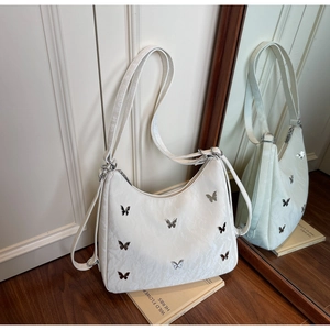 Close-up of white shoulder bag with silver butterfly details and pleated texture