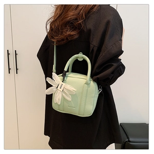 Detail of light green Boston bag with litchi texture and floral pendant charm