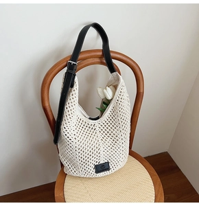Detail of hollow woven shoulder bag with adjustable black leather strap and floral decor