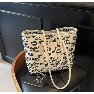 Detailed close-up of leopard print canvas tote bag featuring dual handles and brand tag