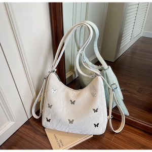 Close-up of white underarm bag with silver butterfly studs and jacquard fabric texture