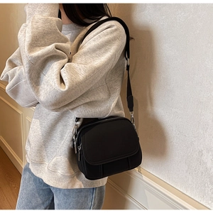 Detail van de zwarte nylon crossbodytas met brede schouderband gedragen door een model