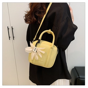 Close-up of bright yellow lychee textured leather mini bag with flower pendant charm