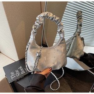 Detailed view of silver crescent bag with rhinestones, pleated handle and chain strap