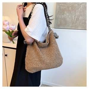 Dettaglio borsa tote in paglia intrecciata con tracolla a nastro a righe bianche e nere