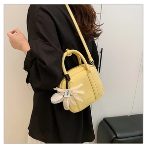 Detail of yellow lychee grain leather boston bag with a white flower charm accessory