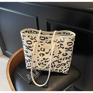 Close-up of leopard print tote bag with leather piping and designer logo detail