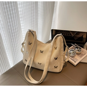 Detail view of cream hobo bag with silver butterfly studs and wide adjustable strap