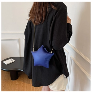 Blue star-shaped crossbody bag with gold chain strap shown on a model perspective