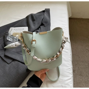 Detail of mint green bucket bag with lychee grain leather and floral silk scarf handle