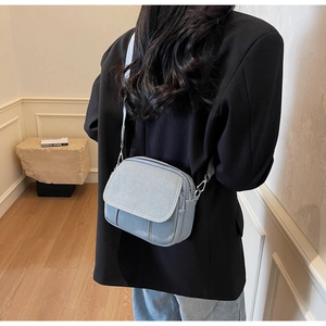 Detail van de lichtblauwe denim crossbodytas met dubbele rits en verstelbare riem