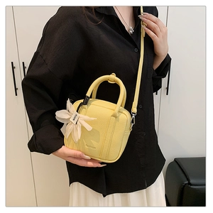 Detail of yellow lychee texture mini Boston bag with floral charm and shoulder strap