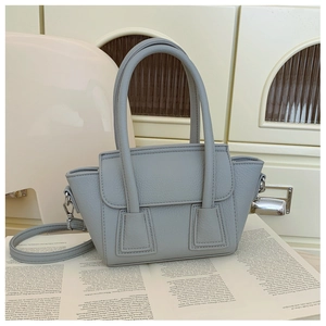 Detail of light blue pebble leather bucket bag with top handles and adjustable strap