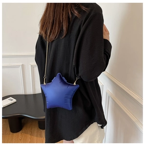 Blue 3D star-shaped crossbody bag with gold chain strap shown on a female model