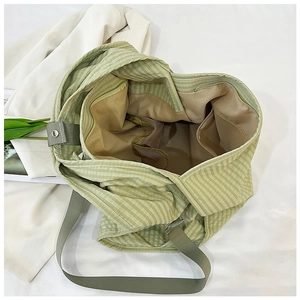 Detailed interior of a green gingham canvas tote bag showing zipper and side pockets