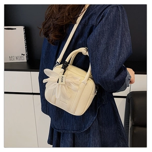 Detail of off-white lychee grain Boston bag with oversized organza flower charm on a model