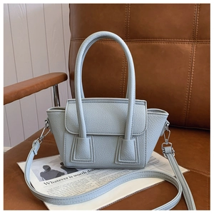 Close-up of light blue-gray lychee leather tote bag with silver hardware on leather seat