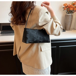 Detail of vintage black underarm bag with textured matte leather worn by a model
