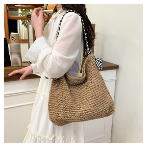 Dettaglio di grande borsa tote intrecciata con manico a foulard a righe in un caffè