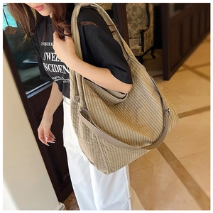 Detailed side view of a khaki checkered canvas tote bag with wide shoulder strap