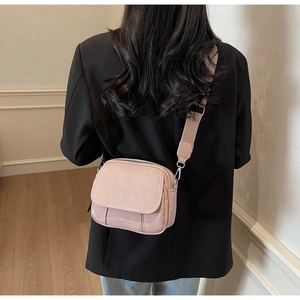 Achteraanzicht van een lichtroze canvas crossbodytas met brede riem bij een model
