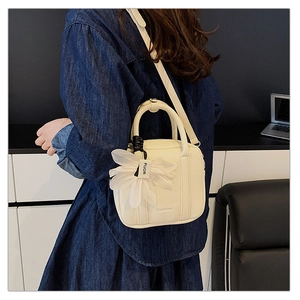 Detail of white Boston bag with litchi texture and a delicate tulle flower charm