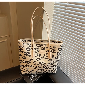 Detail of leopard print canvas tote bag with leather straps and a logo brand patch