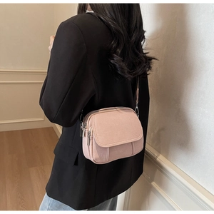 Achteraanzicht van een roze canvas crossbodytas met meerdere ritsen op een model