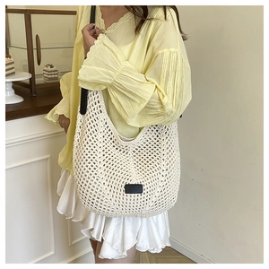 Detail view of woven knit shoulder bag featuring hollow crochet texture and leather accents
