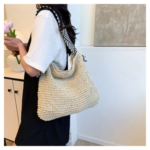 Dettaglio della trama della borsa in paglia beige con tracolla a righe bianche e nere