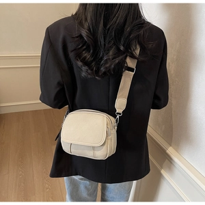 Detail van crème canvas crossbody tas met brede band en dubbele ritsvakken