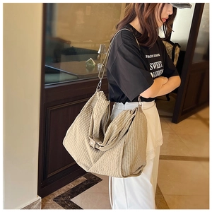 Detail shot of beige plaid canvas tote bag with slim shoulder strap and metal buckle